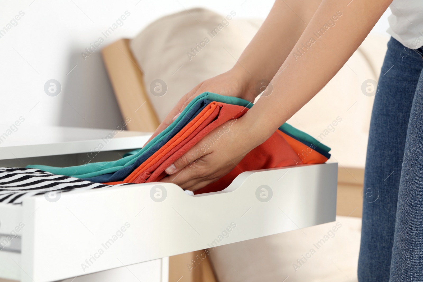 Photo of Woman putting clean clothes into drawer at home, closeup