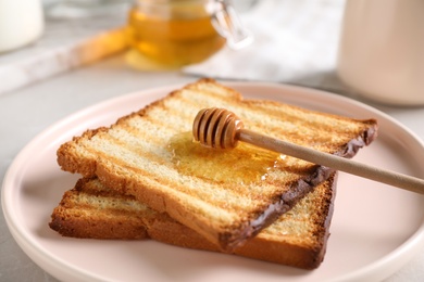 Photo of Tasty toasts with honey served on table, closeup