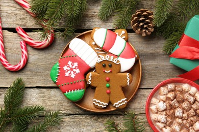 Different tasty Christmas cookies, cocoa with marshmallows and festive decor on wooden table, flat lay