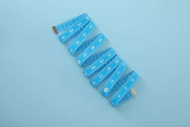 Photo of Measuring tape on light blue background, top view