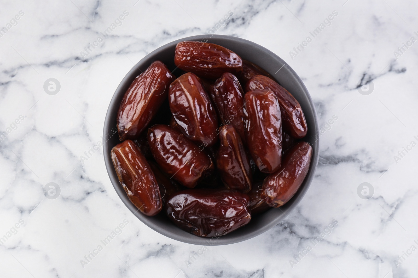 Photo of Sweet dried dates on white marble background, top view
