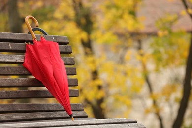 Photo of Red umbrella on bench in autumn park, space for text