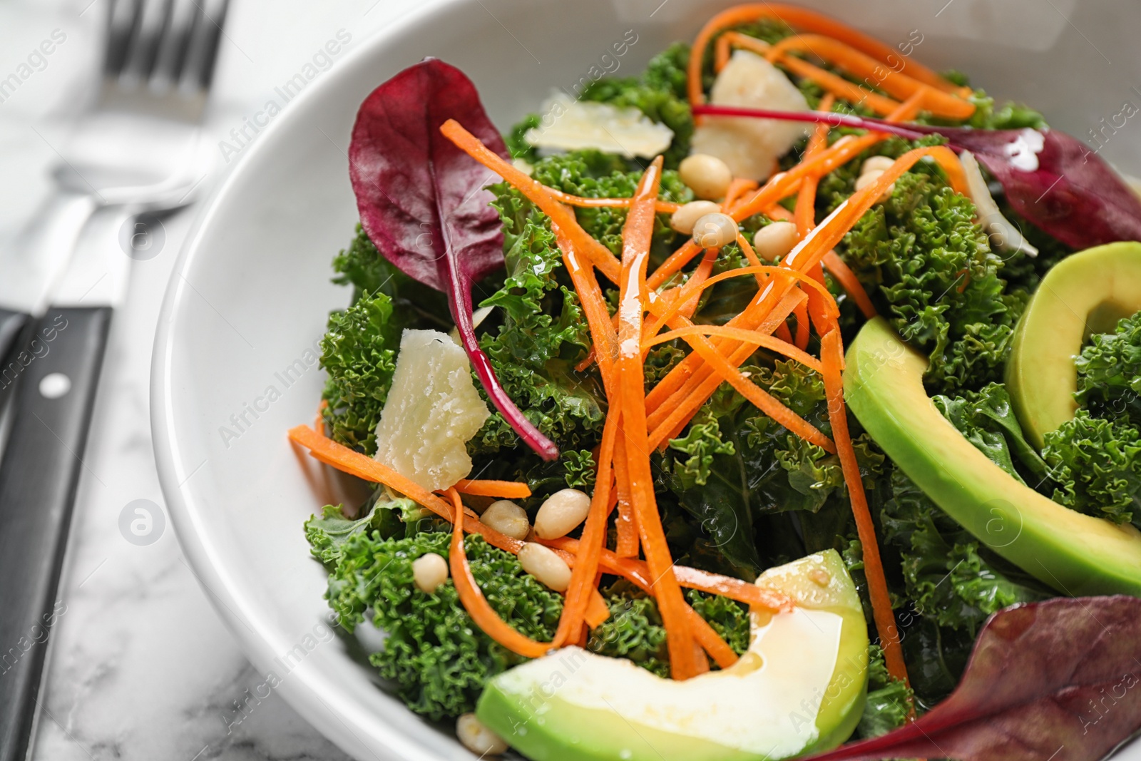 Photo of Tasty fresh kale salad on marble table, closeup