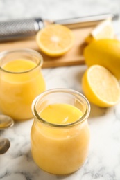 Photo of Delicious lemon curd on white marble table