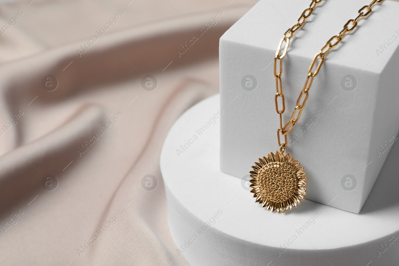 Photo of Stylish presentation of elegant necklace on beige cloth, closeup. Space for text
