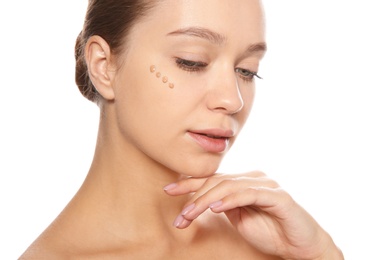 Portrait of young woman with liquid foundation on her face against white background