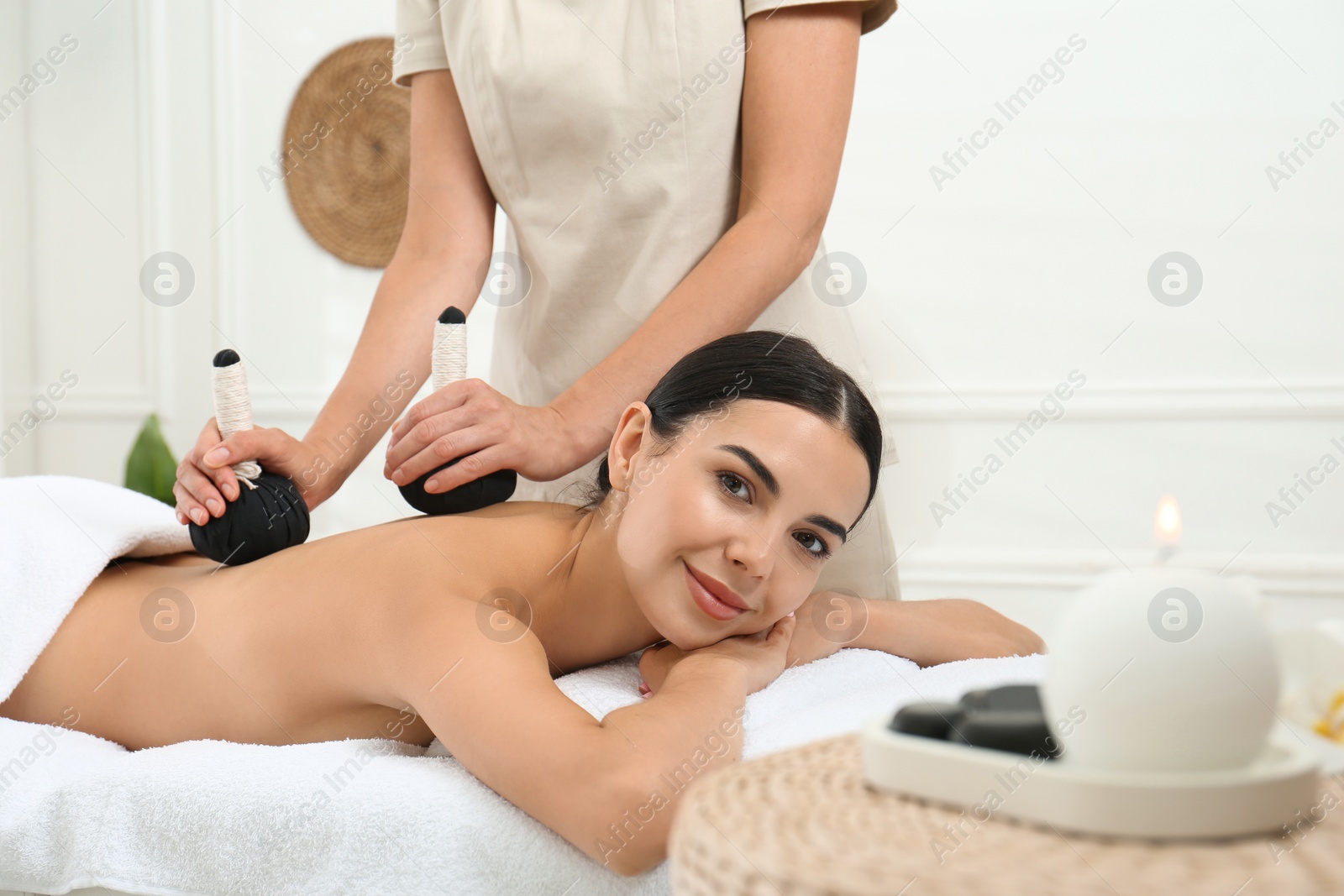 Photo of Young woman receiving herbal bag massage in spa salon