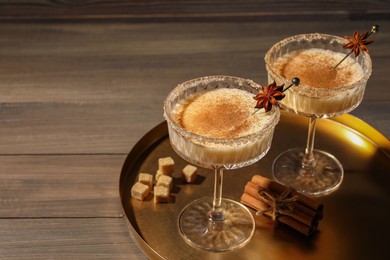 Delicious eggnog with cinnamon and anise on wooden table. Space for text