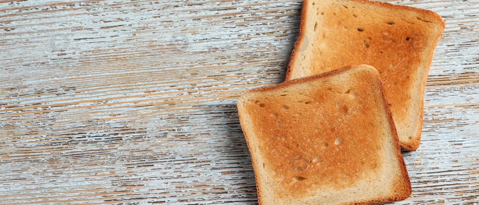 Image of Slices of delicious toasted bread on wooden table, top view with space for text. Banner design