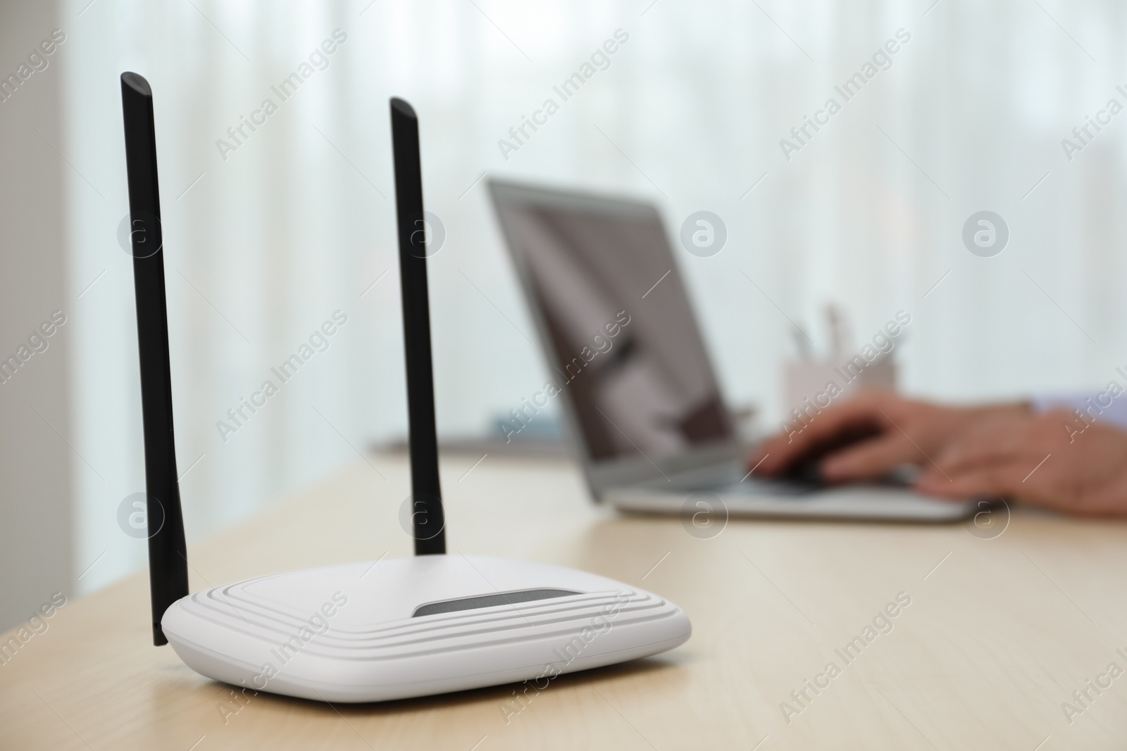 Photo of Man working with laptop in office, focus on router. Wireless internet communication