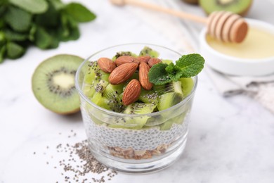 Photo of Delicious dessert with kiwi, chia seeds and almonds on white table, closeup