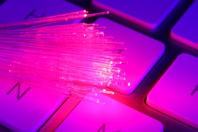 Photo of Optical fiber strands transmitting color light on computer keyboard, macro view