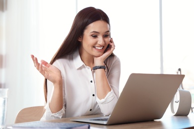 Photo of Young woman using video chat on laptop in home office