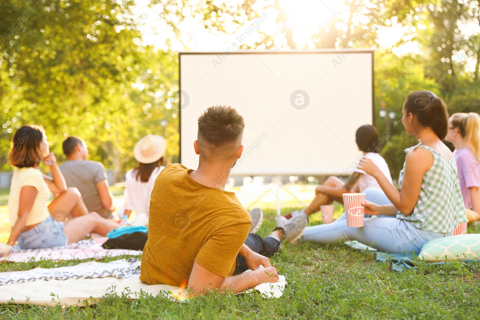 Photo of Young people watching movie in open air cinema. Space for text