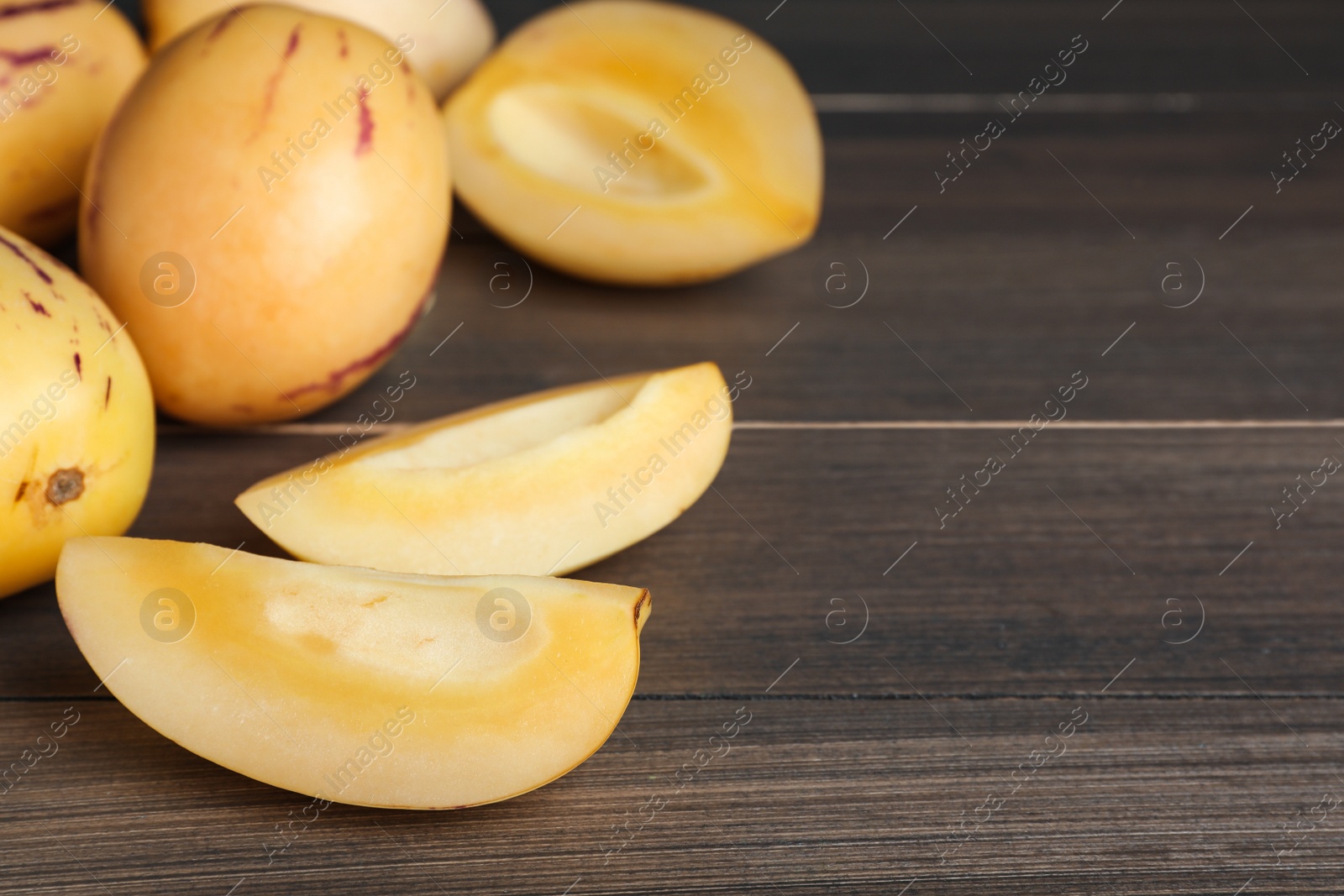 Photo of Cut pepino melon on wooden table, space for text