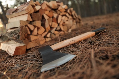 Stack of cut firewood and axe in forest, closeup