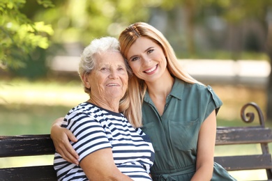 Photo of Woman with elderly mother on bench in park