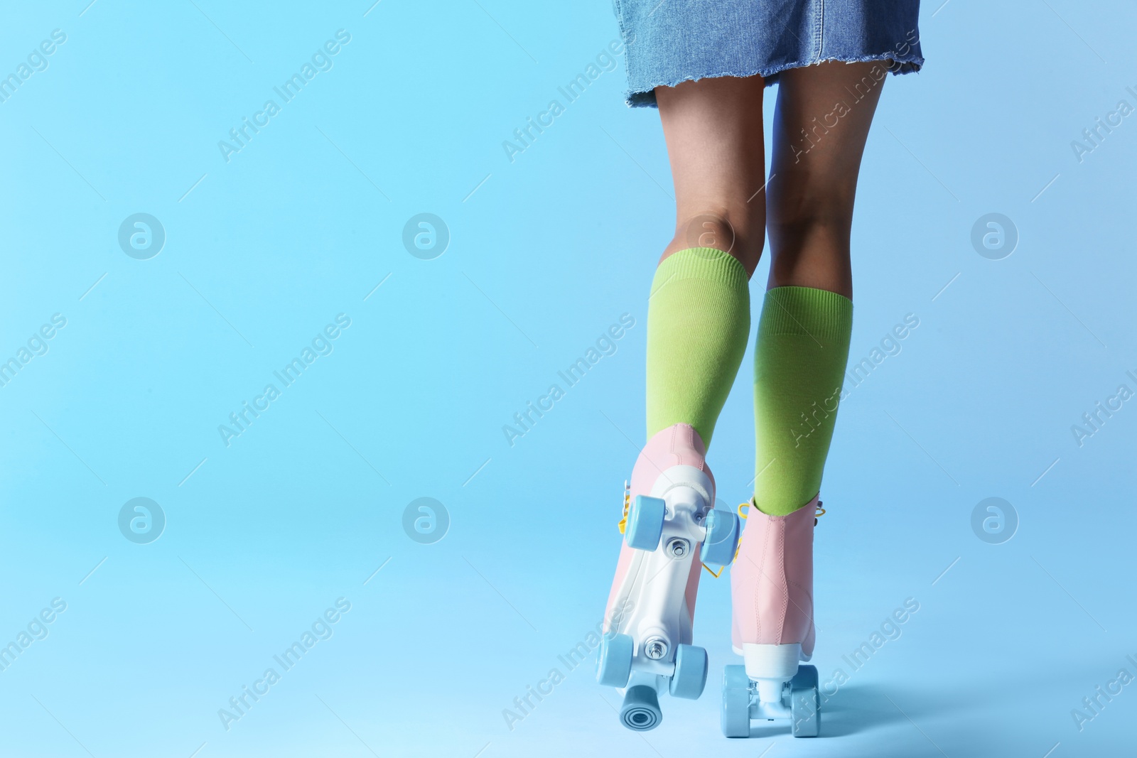 Photo of Woman with vintage roller skates on color background, closeup. Space for text