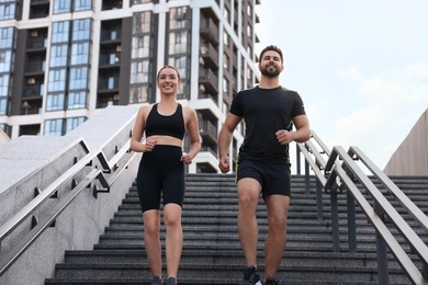 Healthy lifestyle. Happy couple running on steps outdoors, low angle view