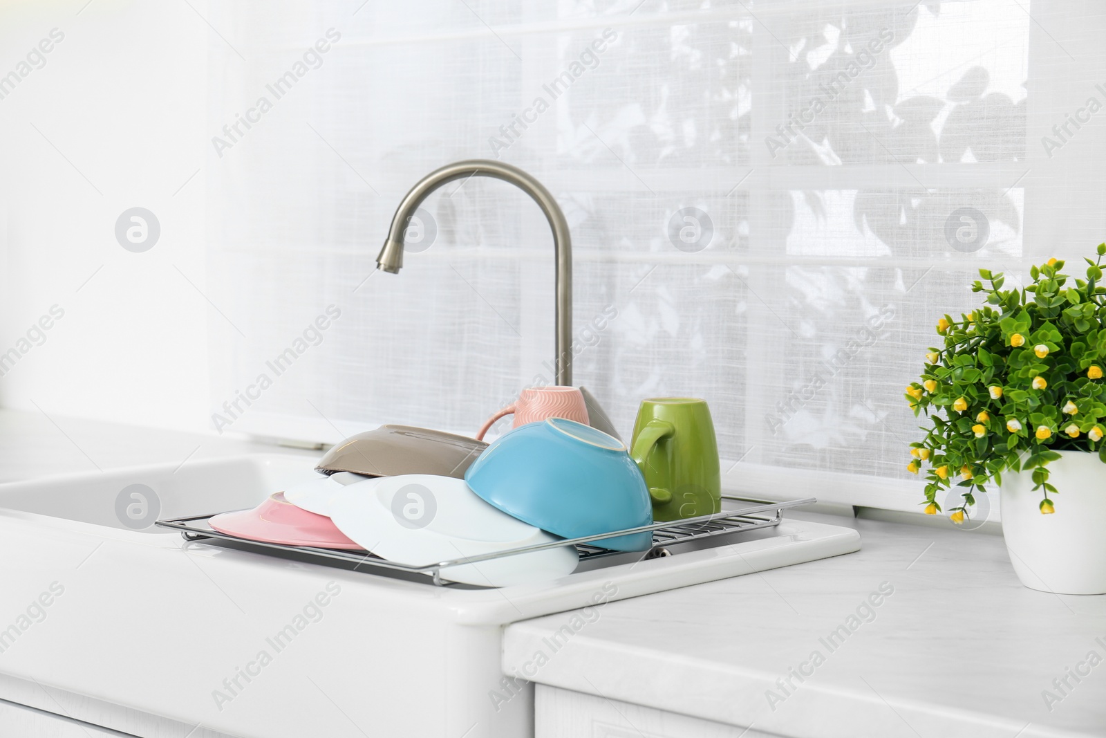 Photo of Drying rack with clean dishes over sink in kitchen