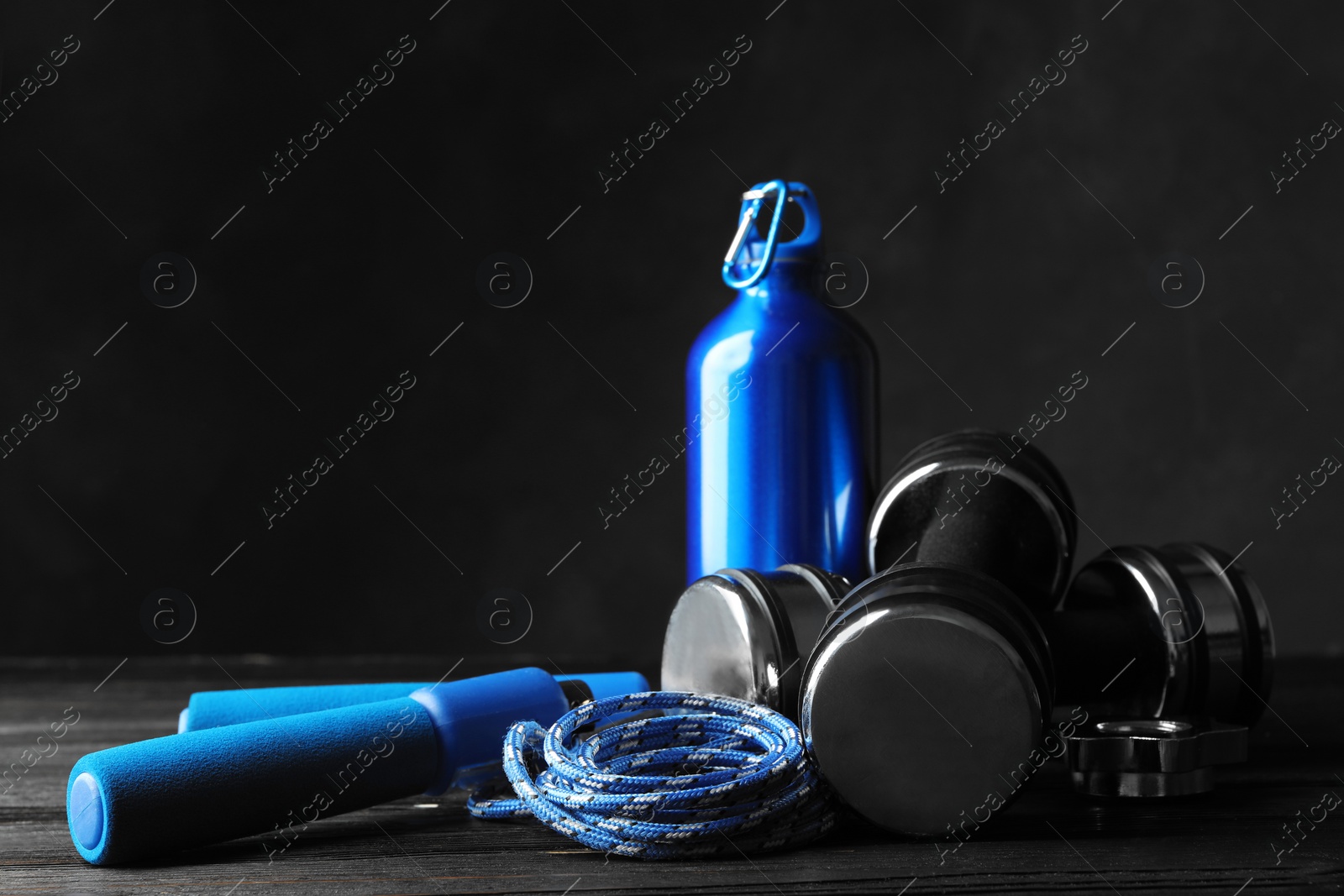 Photo of Gym equipment and accessories on wooden floor against dark background