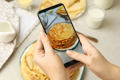 Photo of Blogger taking photo of thin pancakes at table, closeup