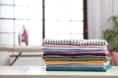 Folded clean clothes on table indoors, space for text. Laundry day