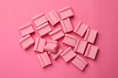 Photo of Tasty chewing gums on pink background, flat lay