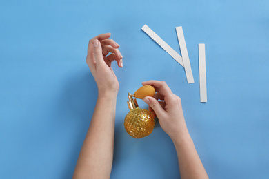 Woman applying perfume on blue background, top view