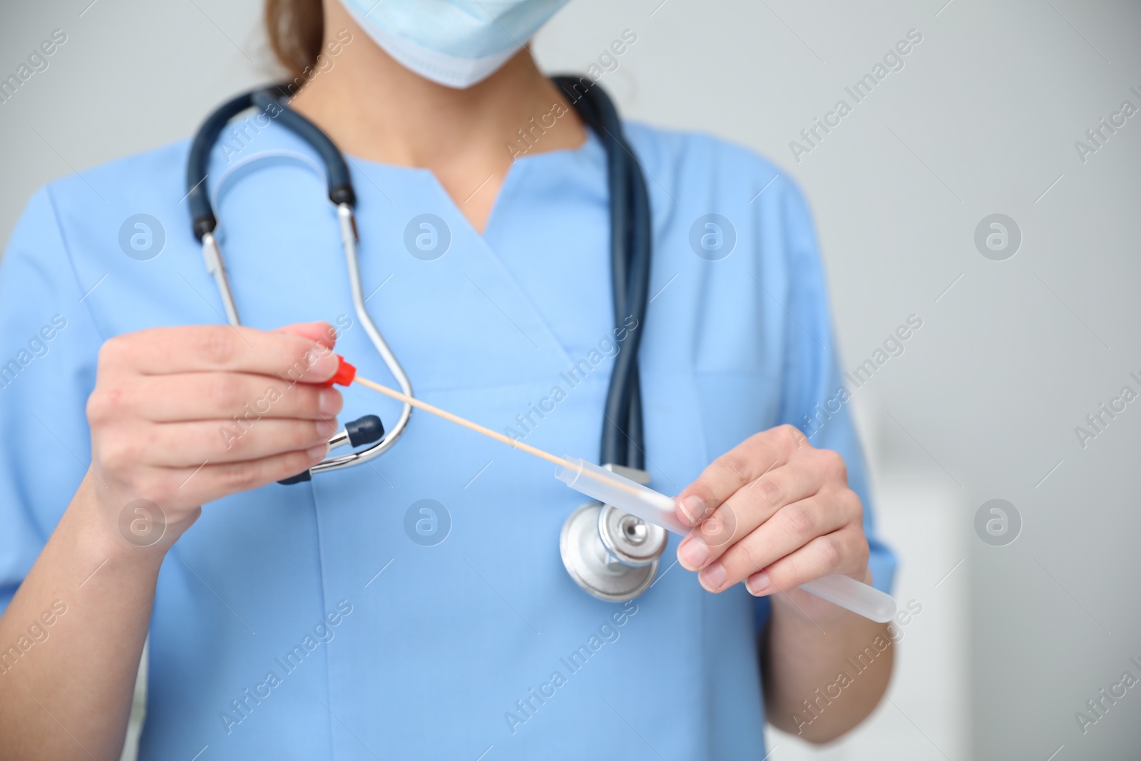 Photo of Doctor holding buccal cotton swab and tube for DNA test in clinic, closeup