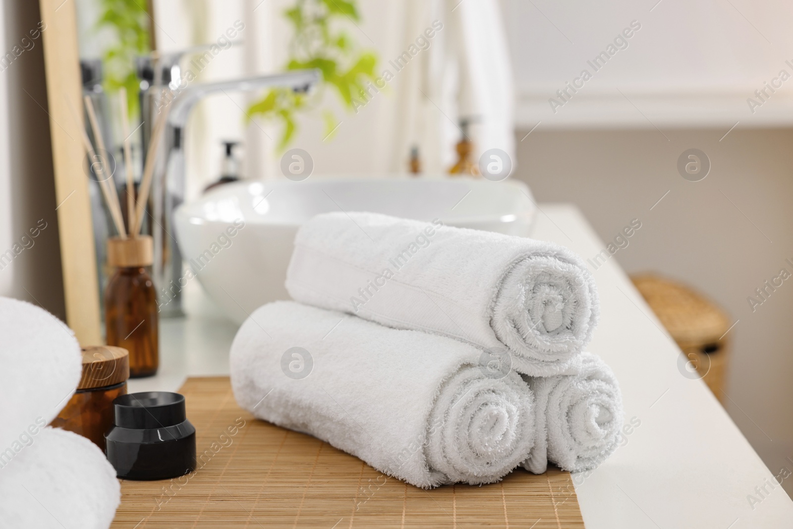 Photo of Rolled soft towels on white table in bathroom