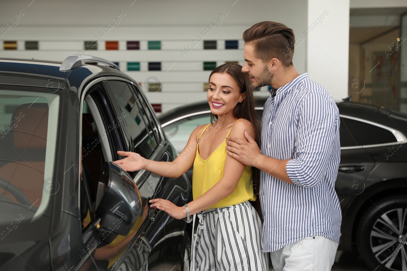 Photo of Young couple choosing new car in salon