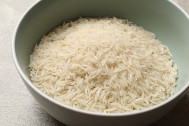 Photo of Raw basmati rice in bowl on grey table, closeup