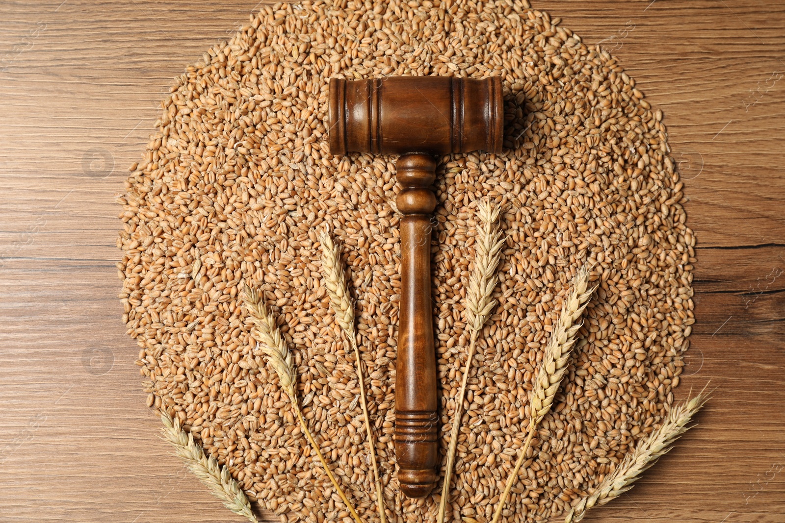 Photo of Judge's gavel, wheat ears and grains on wooden table, top view. Agricultural deal