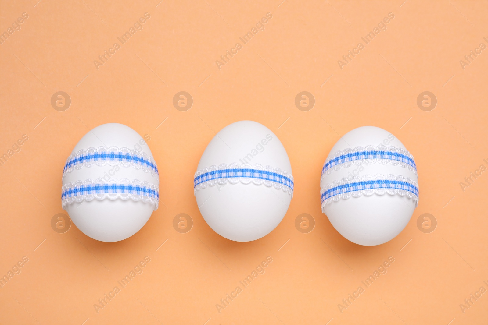 Photo of Beautifully decorated Easter eggs on pale orange background, flat lay