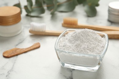 Photo of Tooth powder and brushes on white marble table, closeup