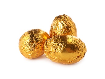 Chocolate eggs wrapped in golden foil on white background