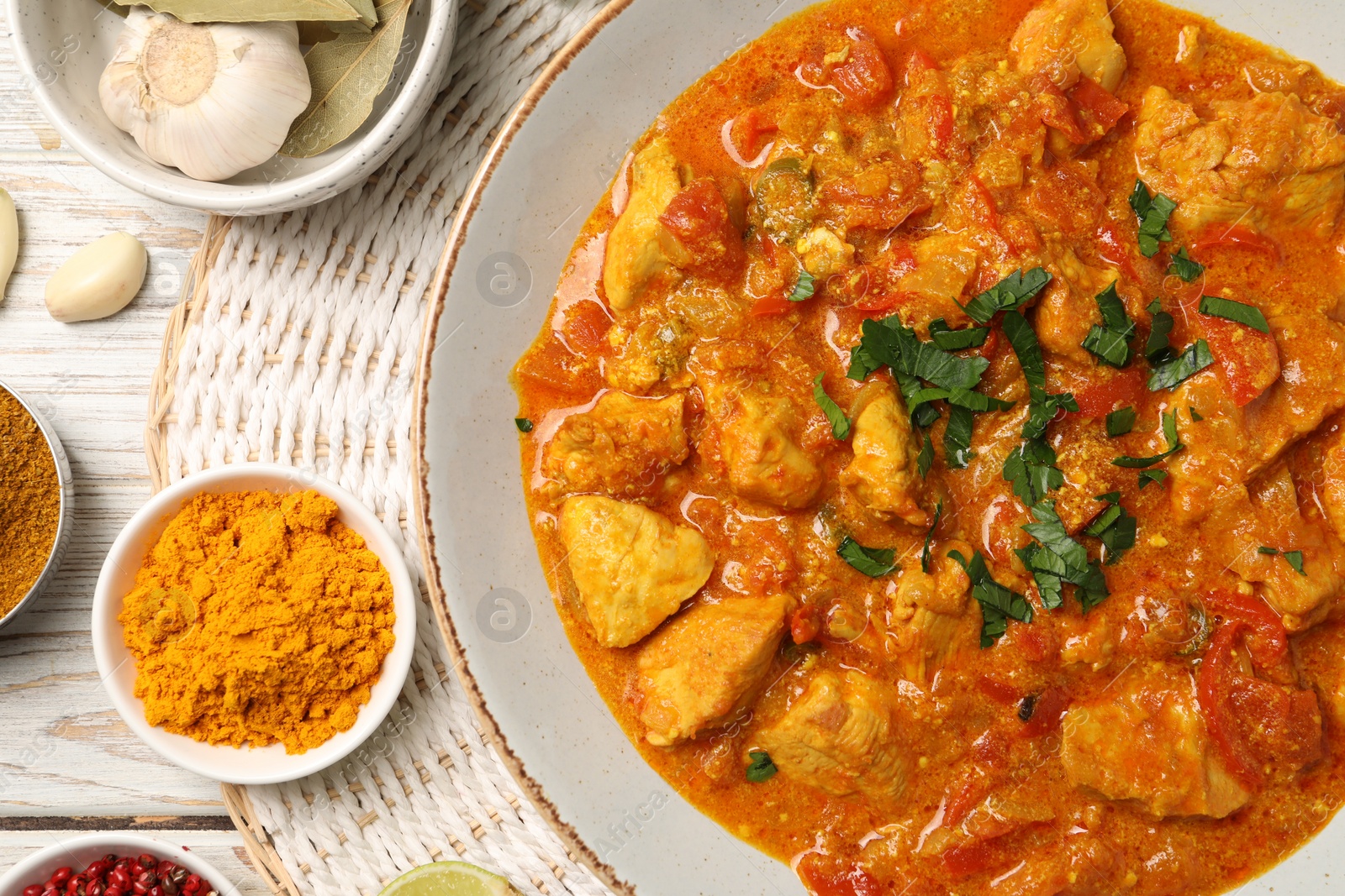 Photo of Delicious chicken curry and ingredients on wooden table, flat lay