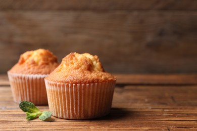 Delicious sweet muffins on wooden table, closeup. Space for text