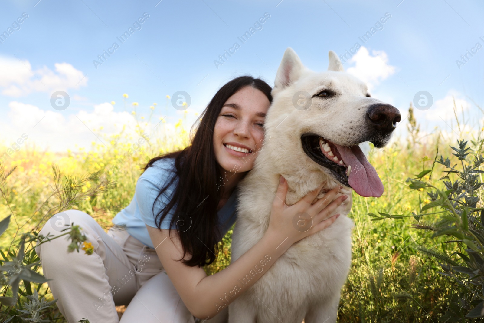 Photo of Teenage girl hugging her white Swiss Shepherd dog in park