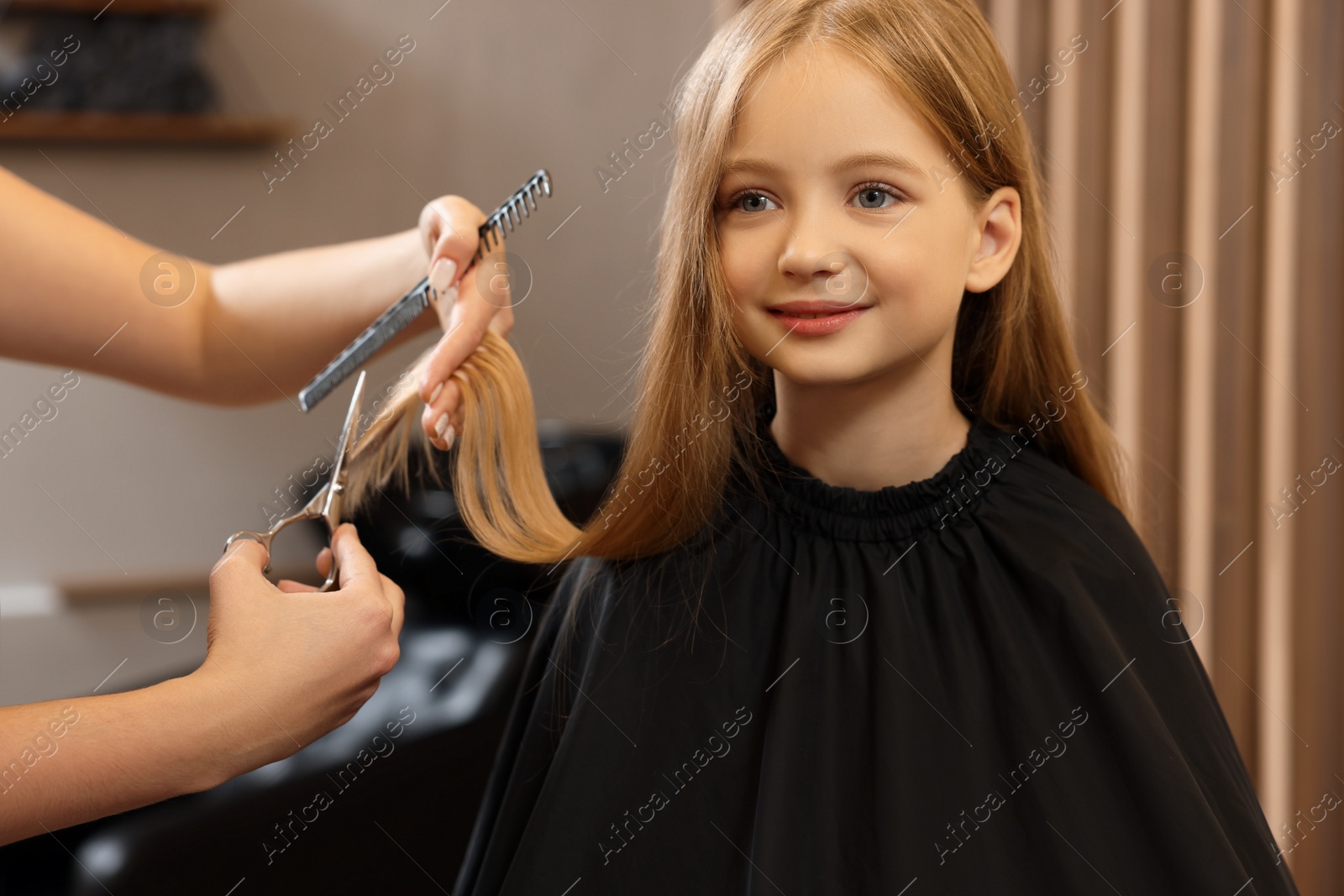 Photo of Professional hairdresser cutting girl's hair in beauty salon