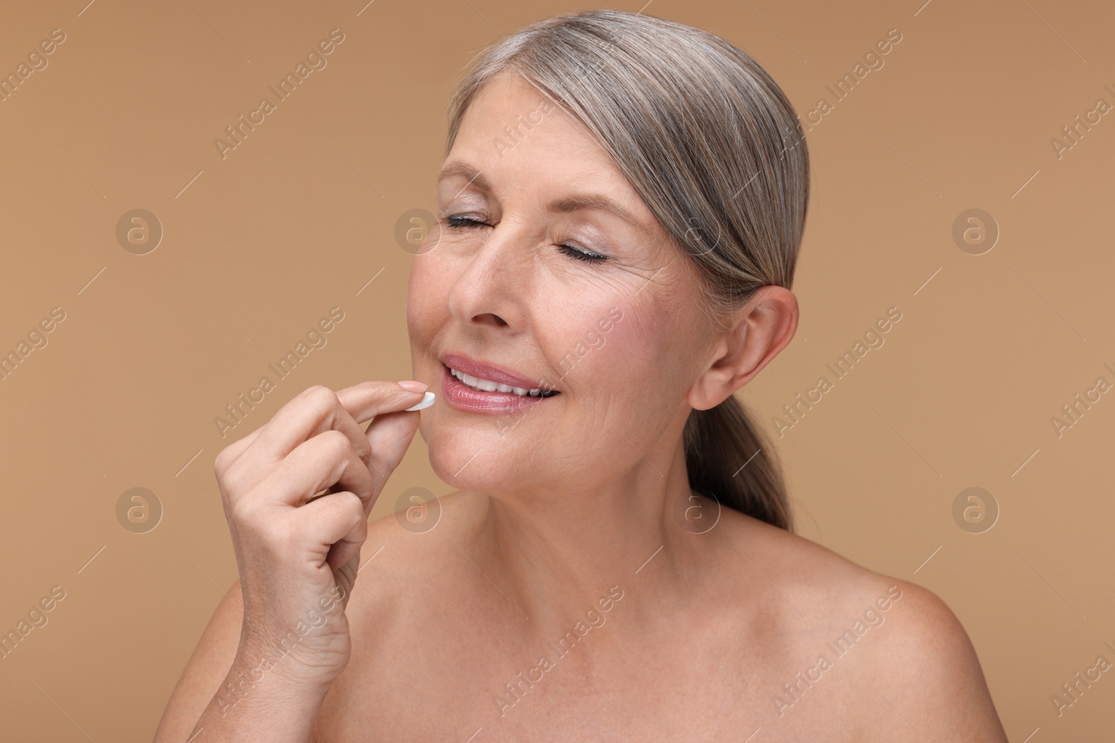 Photo of Beautiful woman taking vitamin pill on beige background