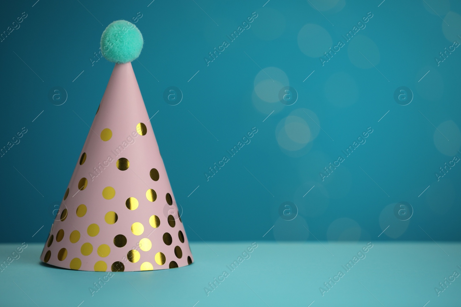 Photo of Pink party hat on light blue background, space for text