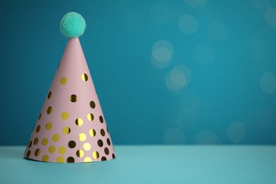 Pink party hat on light blue background, space for text