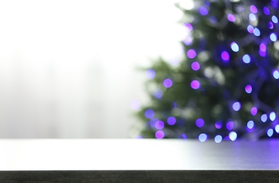 Photo of Empty table and blurred fir tree with violet Christmas lights on background, bokeh effect. Space for design