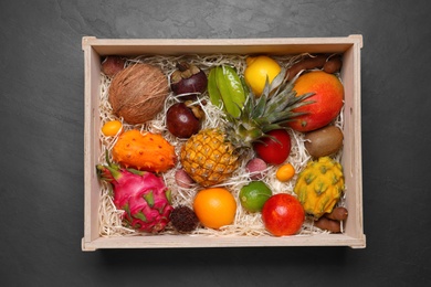 Photo of Crate with different exotic fruits on black table, top view