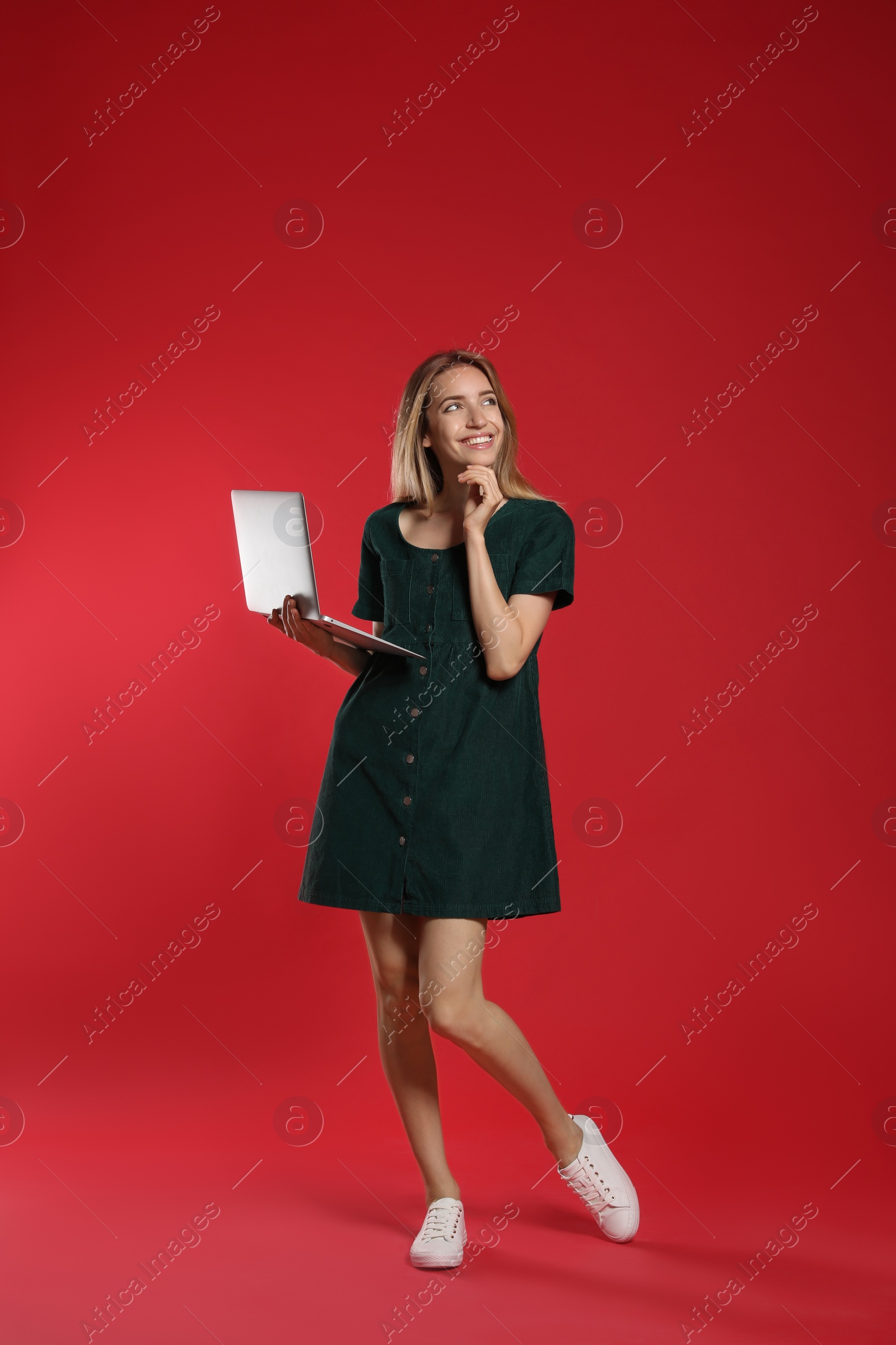 Photo of Full length portrait of happy woman with modern laptop on red background