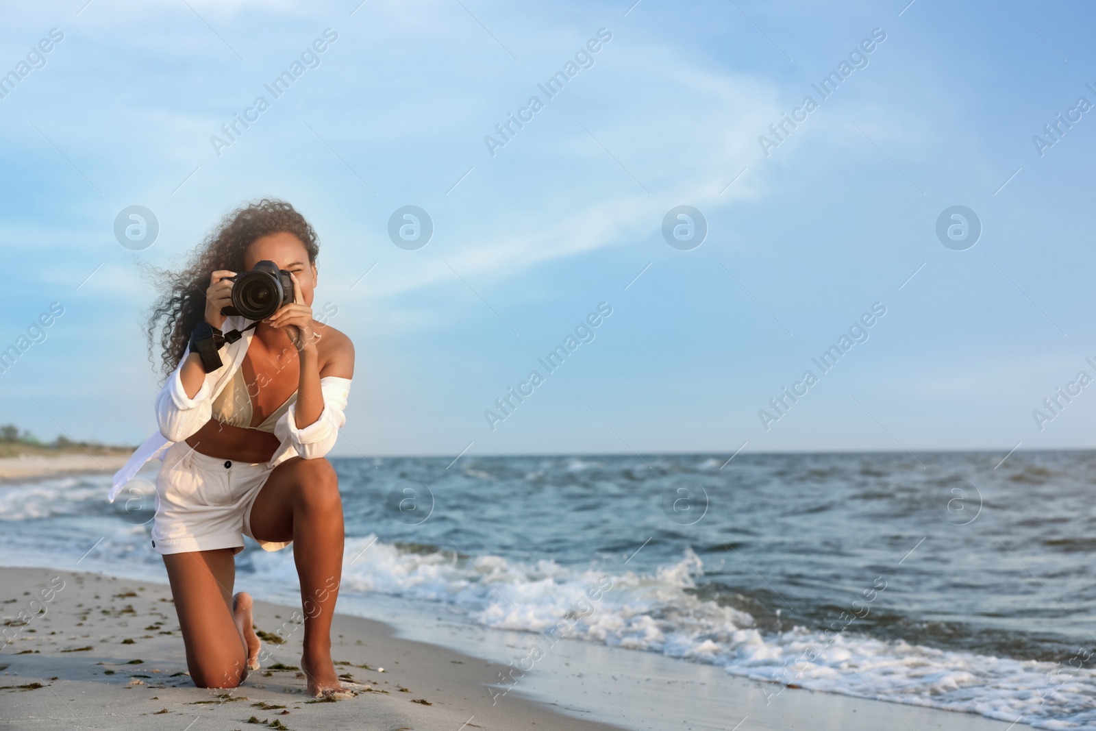 Photo of African American photographer taking photo with professional camera near sea