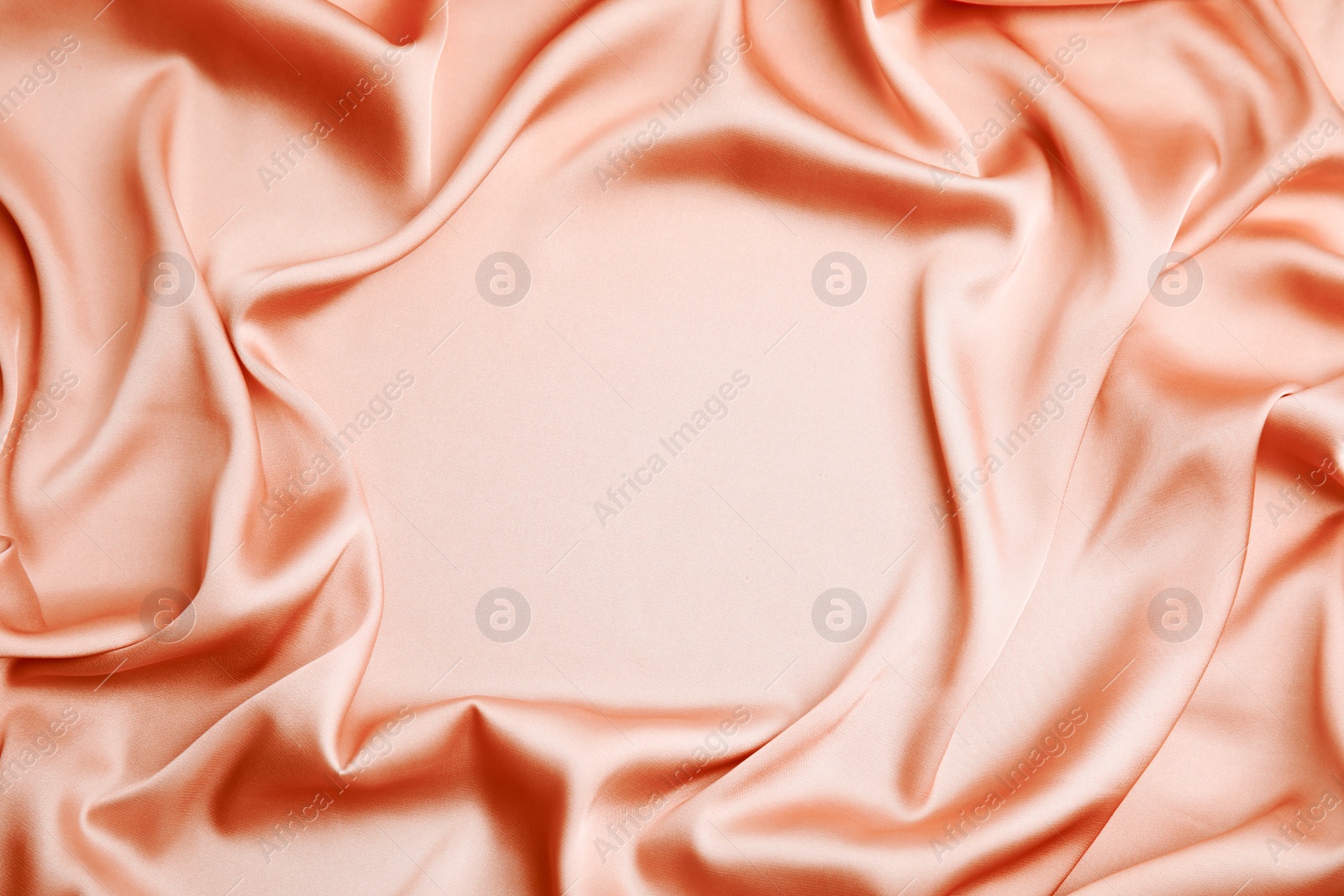 Image of Delicate pale orange silk fabric as background, top view. Space for text