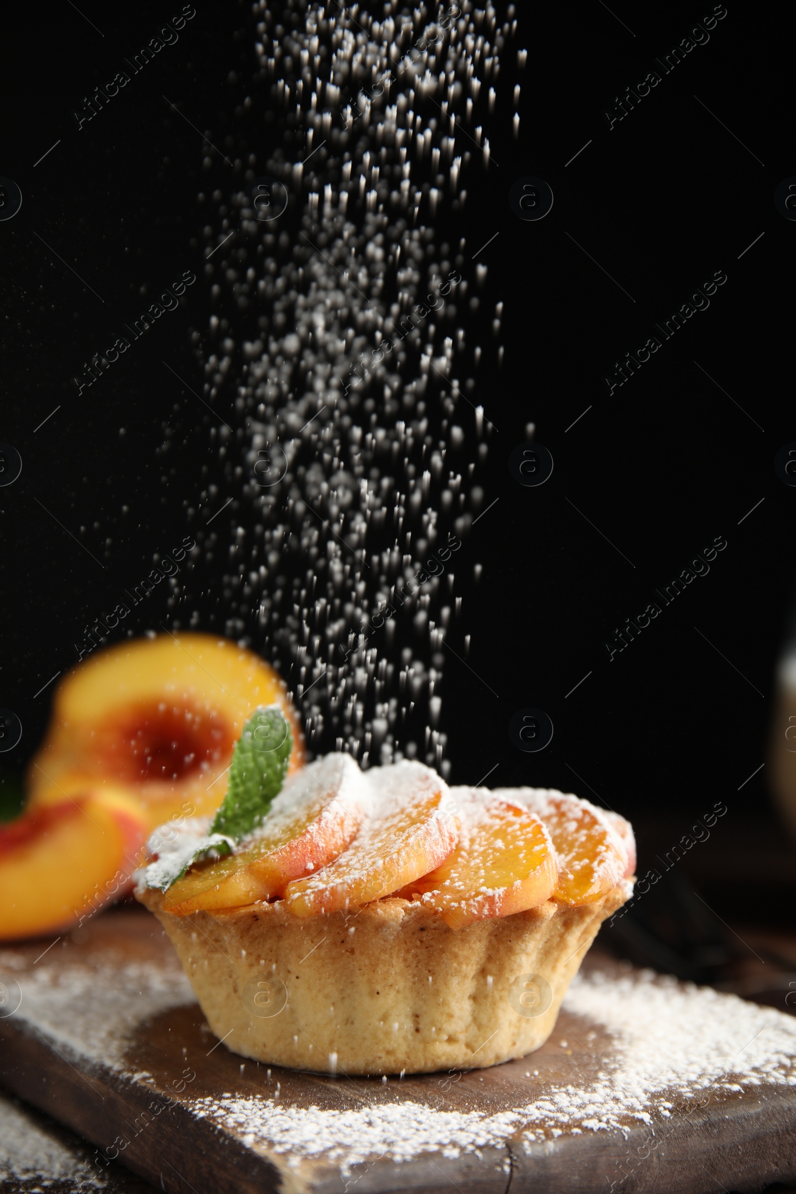 Photo of Decorating delicious peach dessert with powdered sugar on wooden board